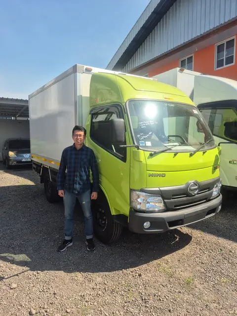 Sales dealer Hino resmi berjabat tangan dengan customer di depan unit Hino 300 box baru