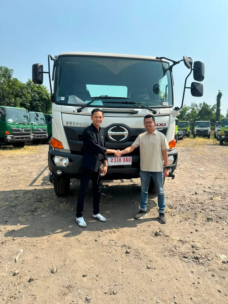 Sales dealer Hino resmi berjabat tangan dengan customer di depan unit Hino 500 baru
